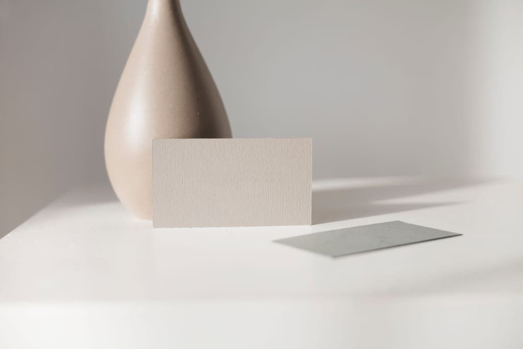 Textured stationery and a ceramic vase in warm afternoon light